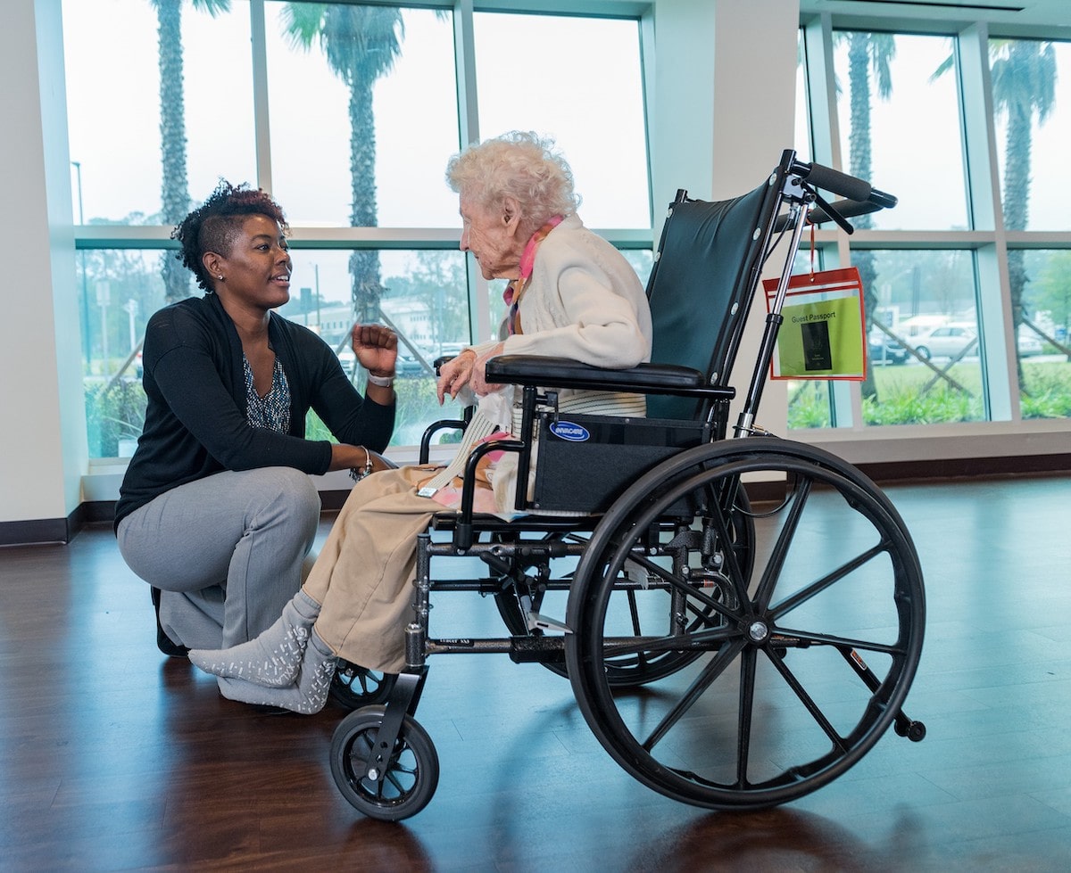 Nursing home nurse talking to senior patient in wheelchair